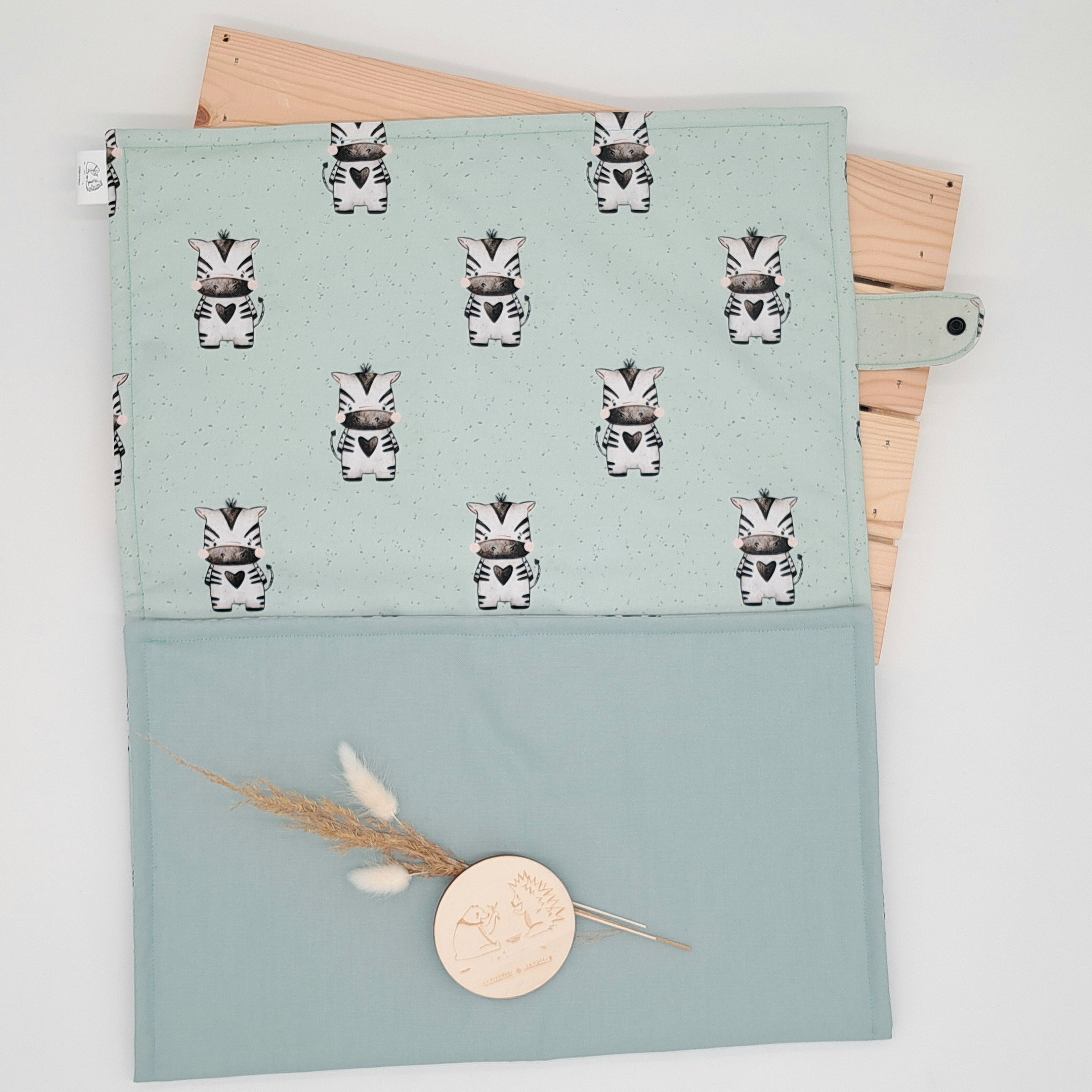 Wickelunterlage zum Mitnehmen für das praktische Wickeln unterwegs. Die Unterlage ist ca. 43cm X 80cm groß, bestehend aus zwei Stofflagen und einer leichten Polsterung.