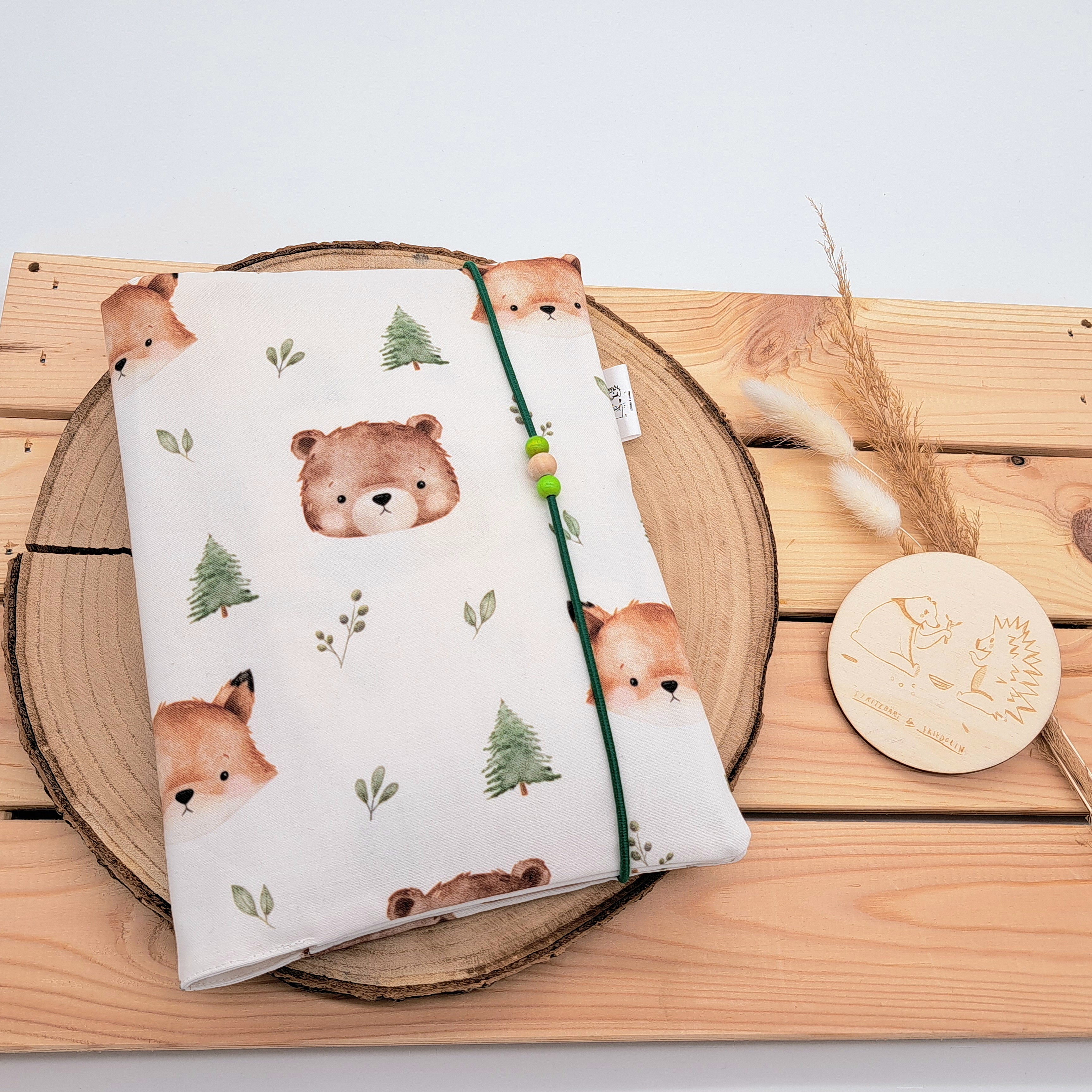 Handgefertigte Windeltasche aus 100% Bio-Baumwolle mit Fach für Windeln und Feuchttücher, Gummikordel-Verschluss mit Holzperlen; nachhaltiges und praktisches Accessoire für Eltern unterwegs. Neutrales Motiv mit Bären, Fuchs, Bäumen und Blättern.